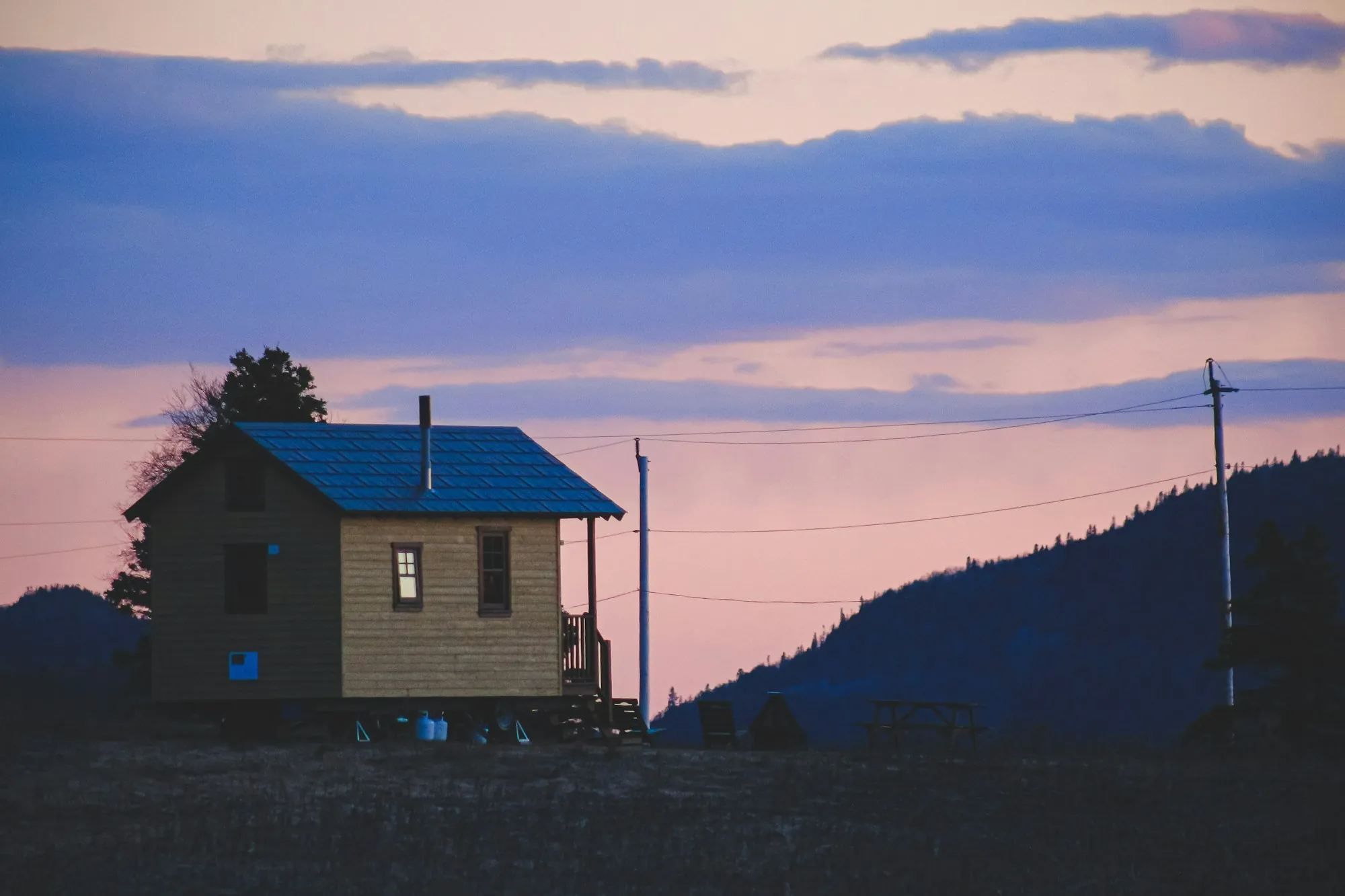 Small cabin with a blue metal roof at sunset, the kind of metal roof vs shingles choice Hapeville homeowners weigh