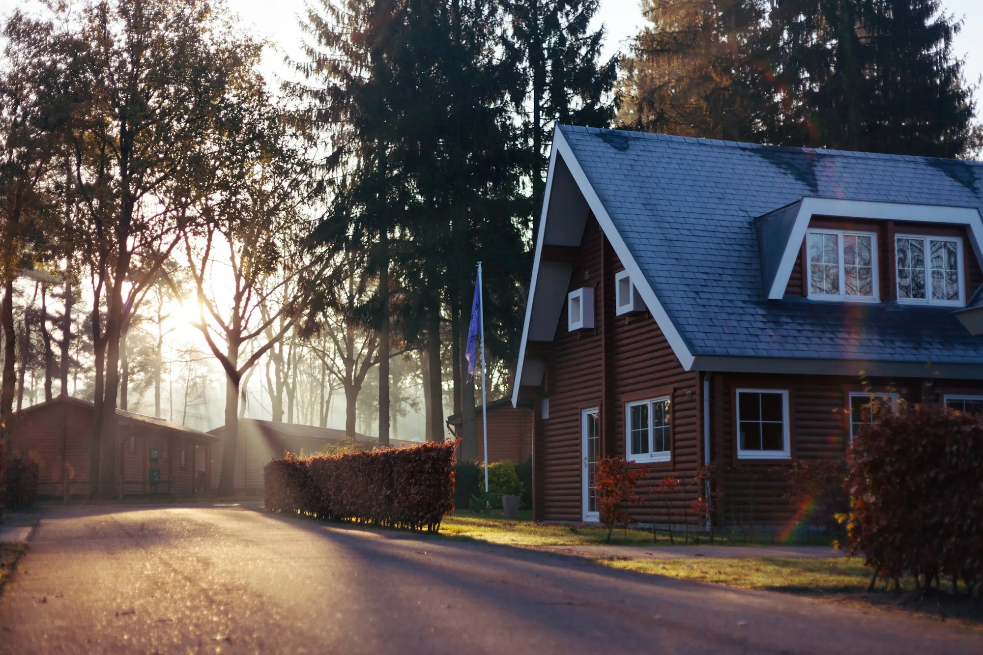 Brick cottage with a dark shingle roof and dormer windows in morning light