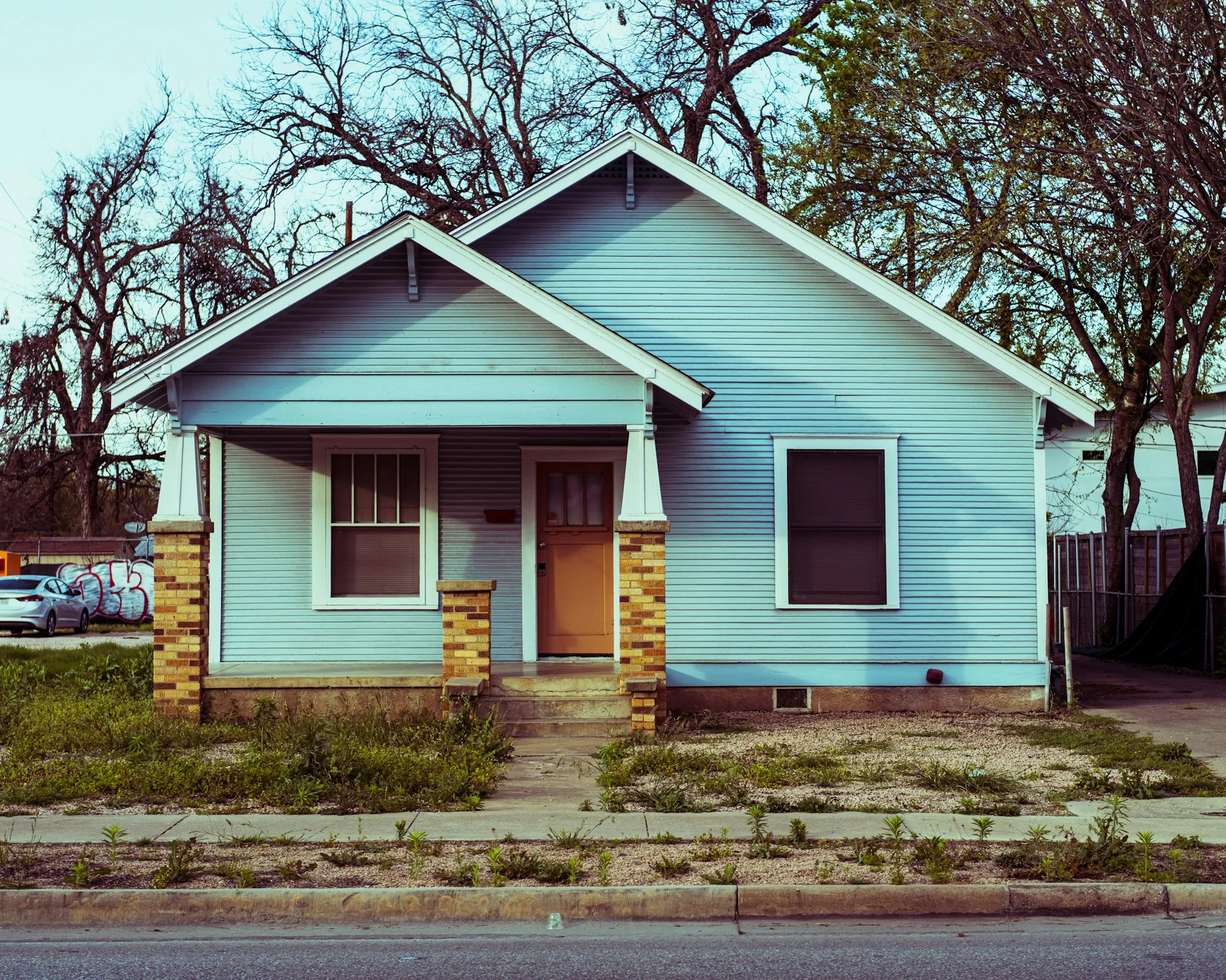 Light blue bungalow with a front porch on a quiet street